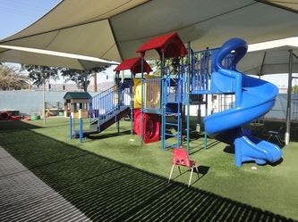 Playground with blue slides and red structures under a shade canopy