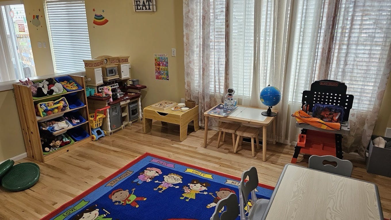 Children's playroom with toys, a rug, small tables, and chairs