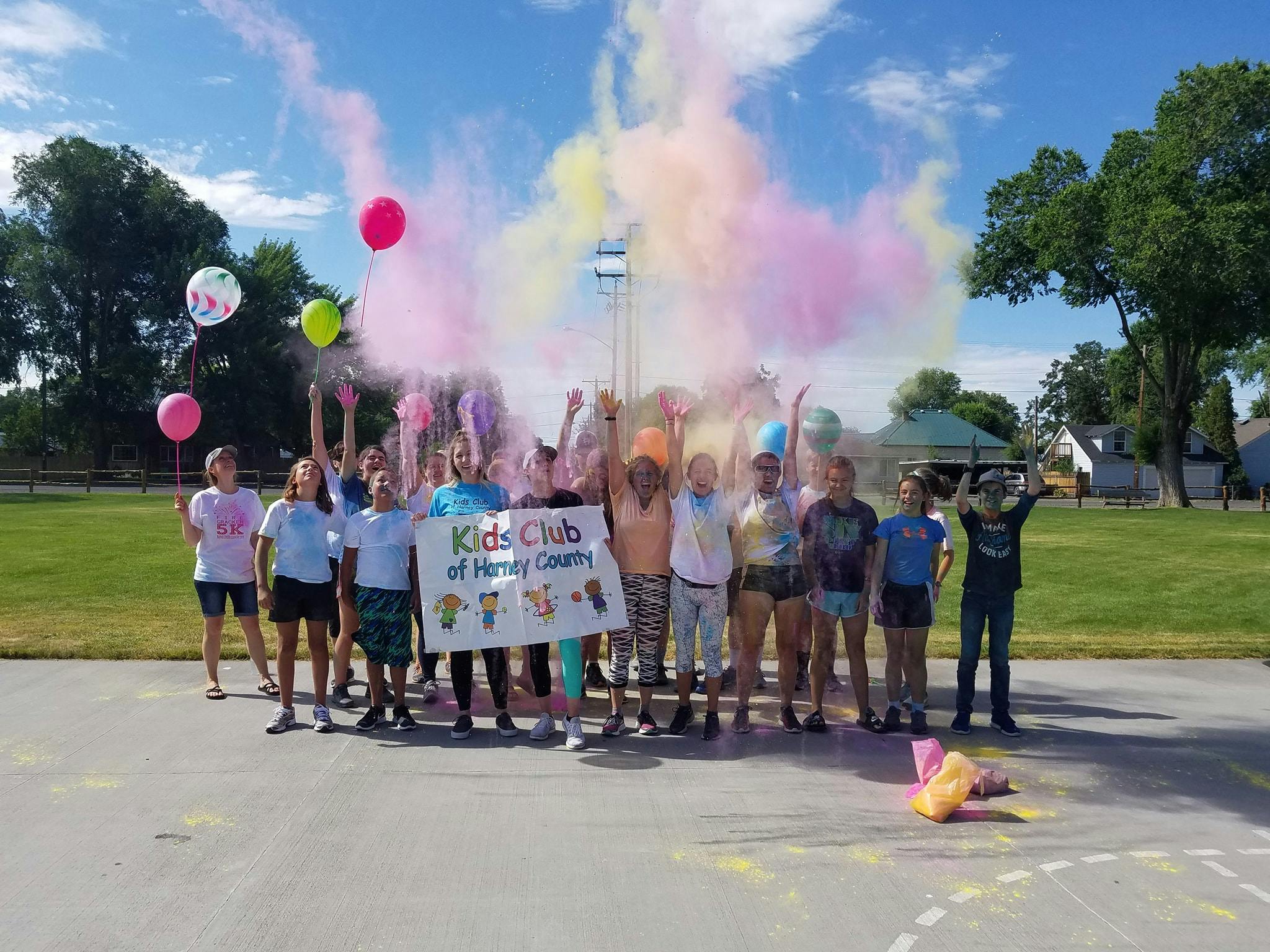 Group of children holding a banner with colorful powder exploding around them