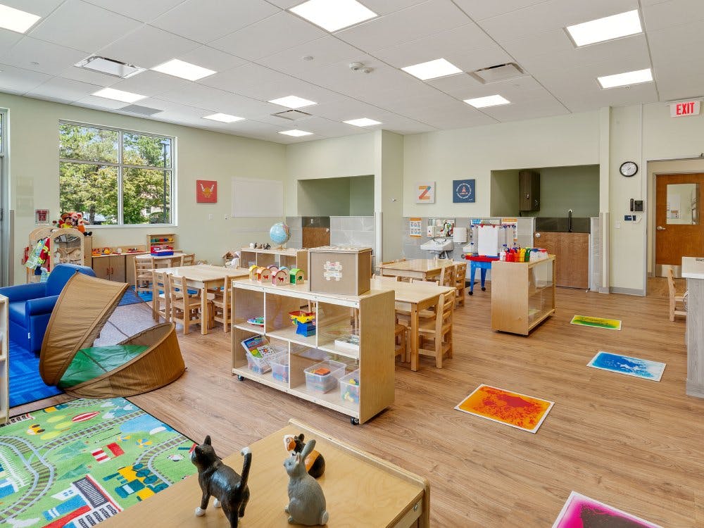Classroom with small tables, chairs, and play equipment