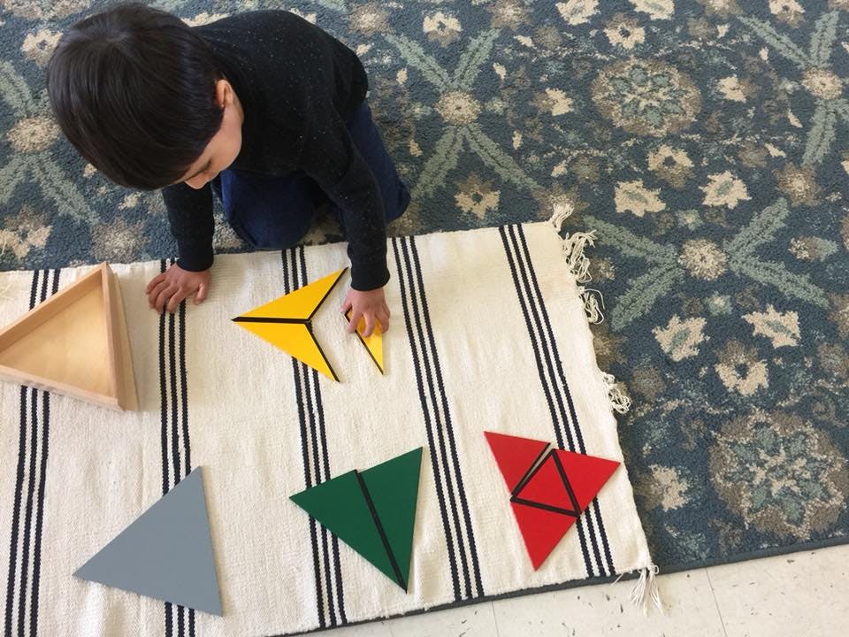 Child playing with colorful triangle shapes on a striped mat