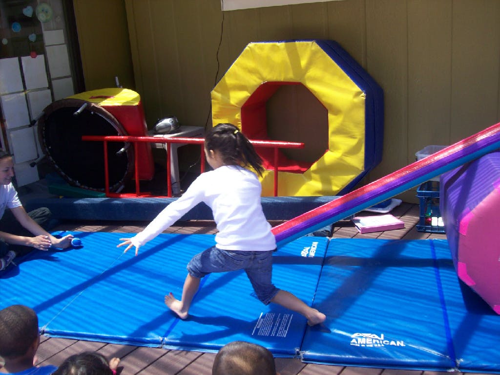 Child on blue mat reaching out with arm