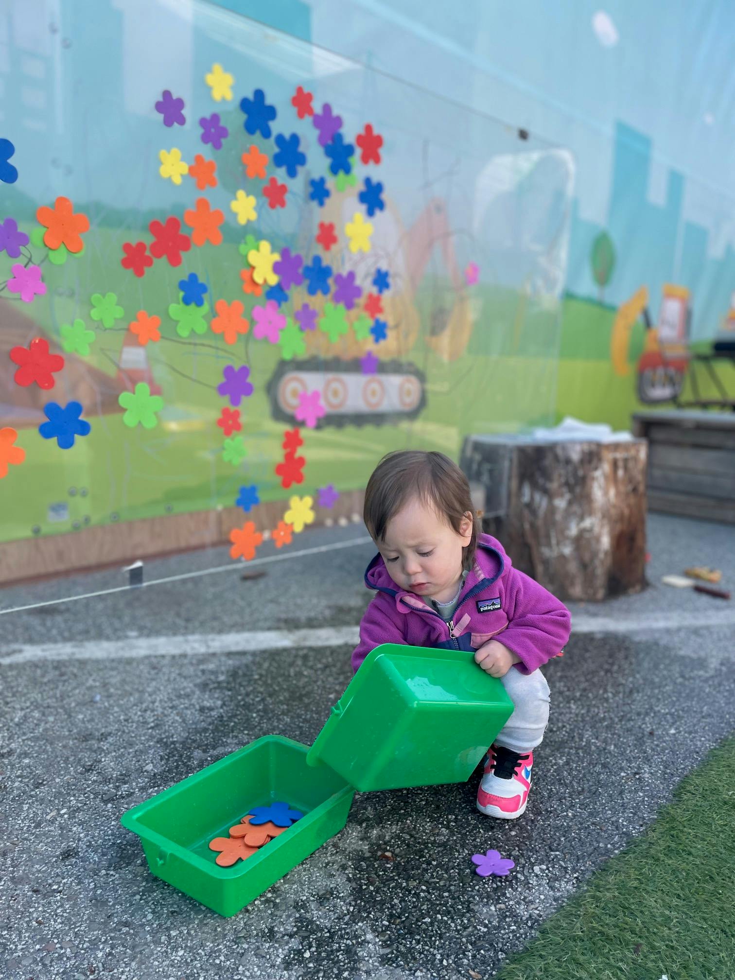 Child playing with green containers and colorful flower shapes