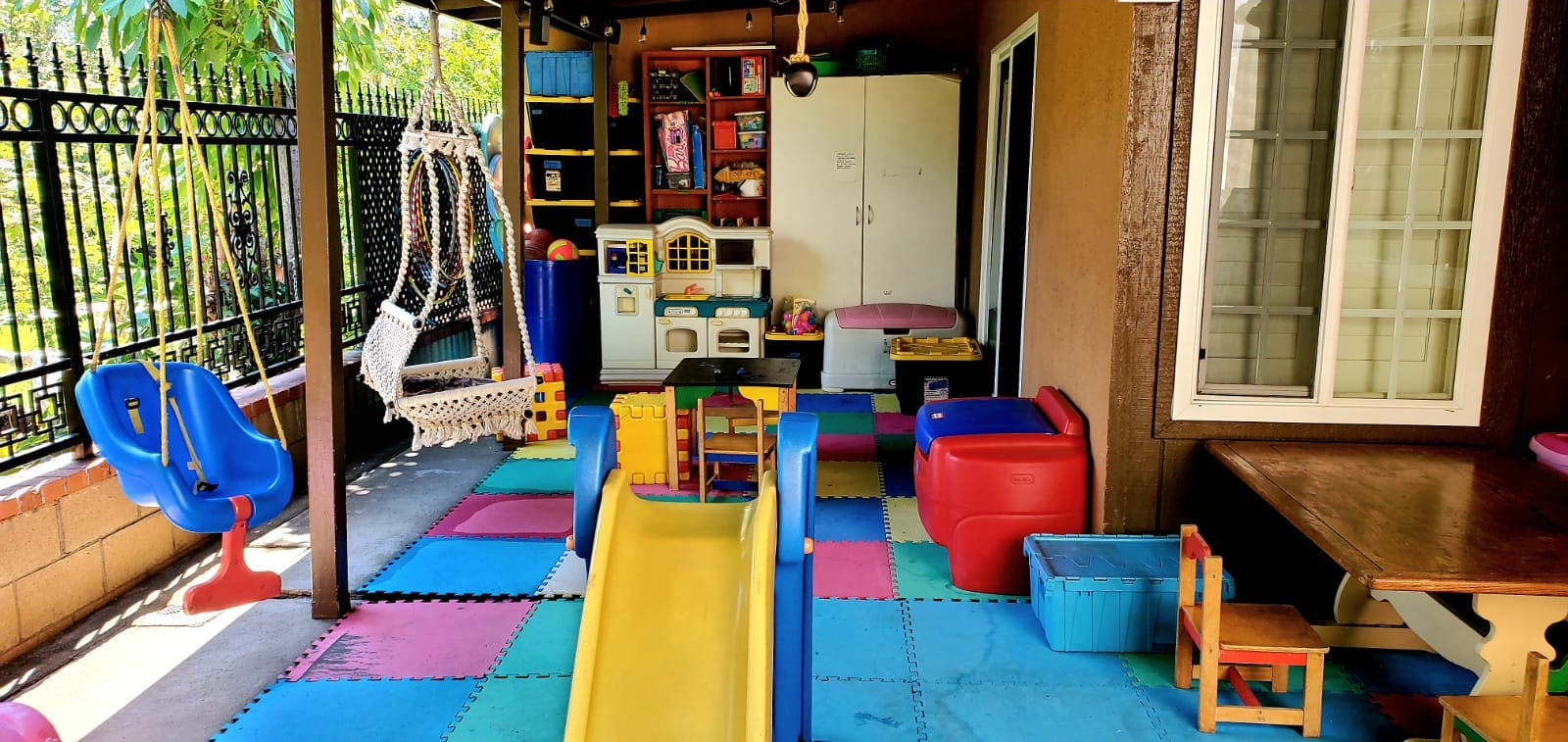 Outdoor play area with swings, slide, and colorful floor mats