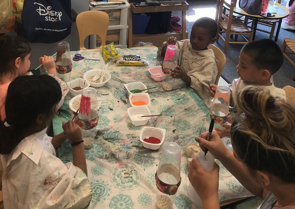 Children painting bottles at a table