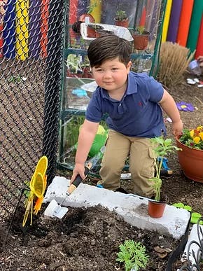 Child kneeling and digging in soil with a trowel
