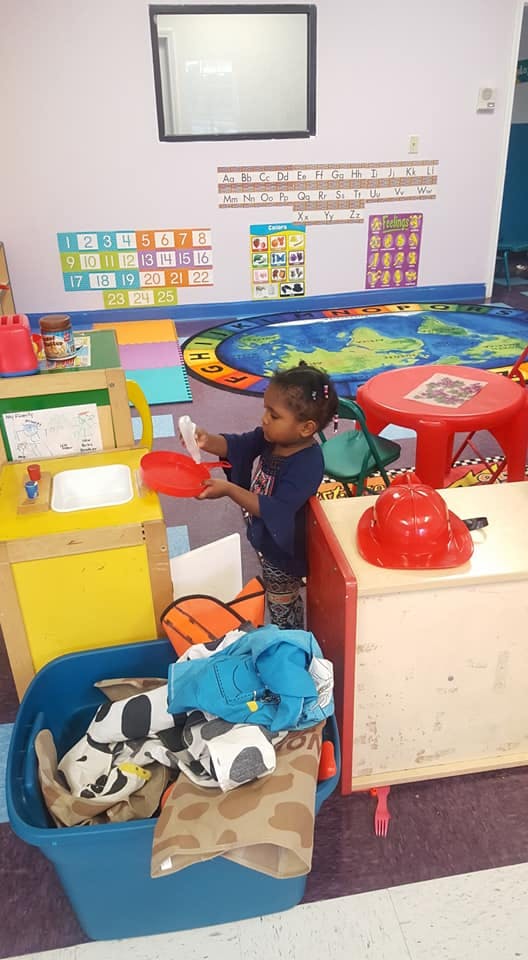 Child playing with toy kitchen set in a classroom