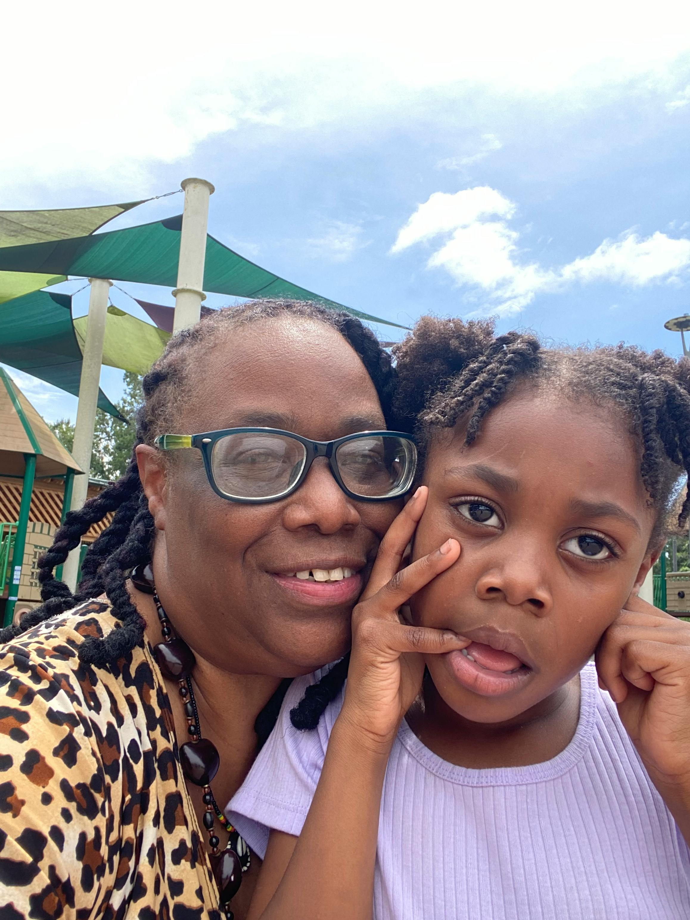 Child making a silly face next to a person in glasses with a leopard print top