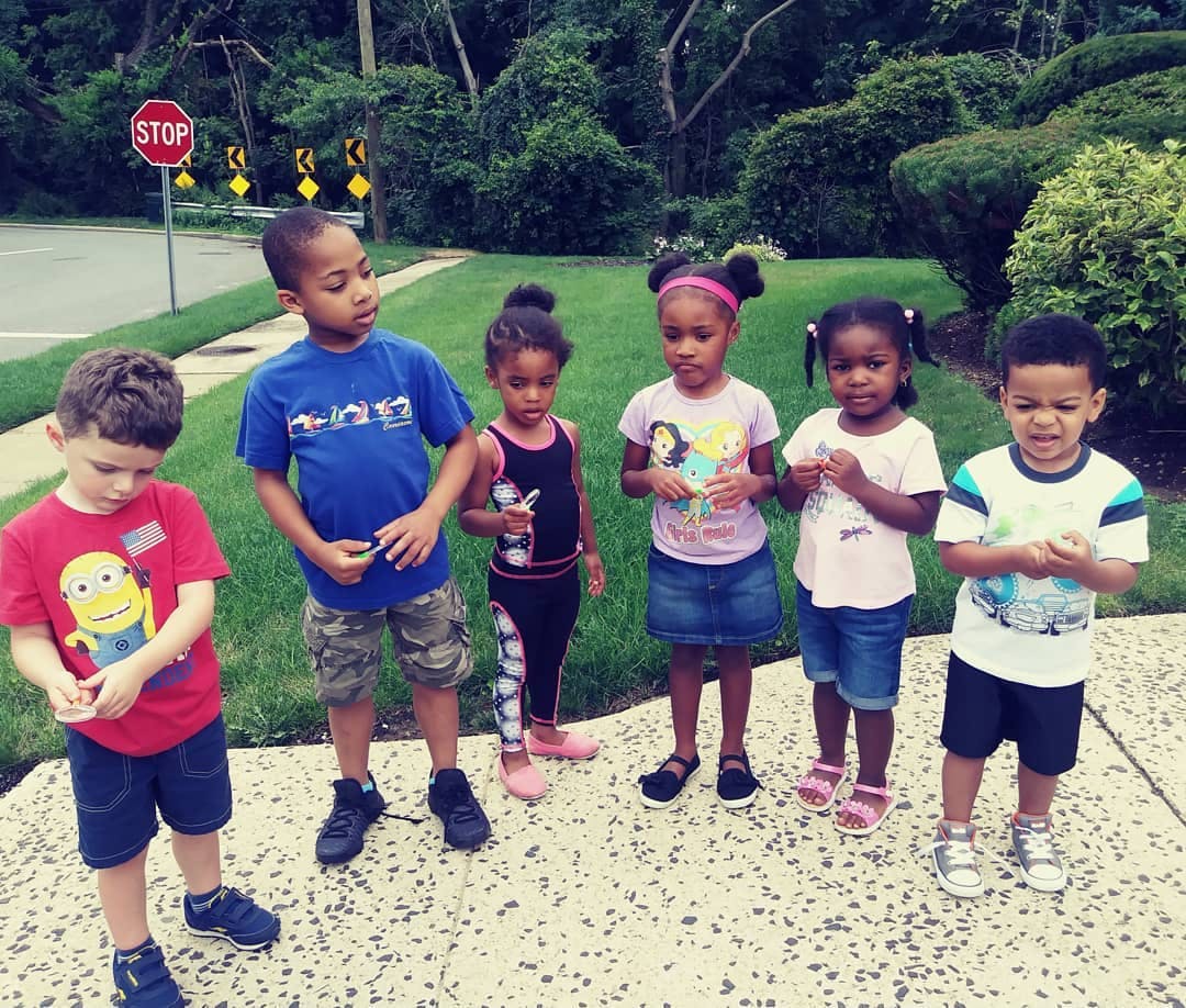 Six children standing on a sidewalk