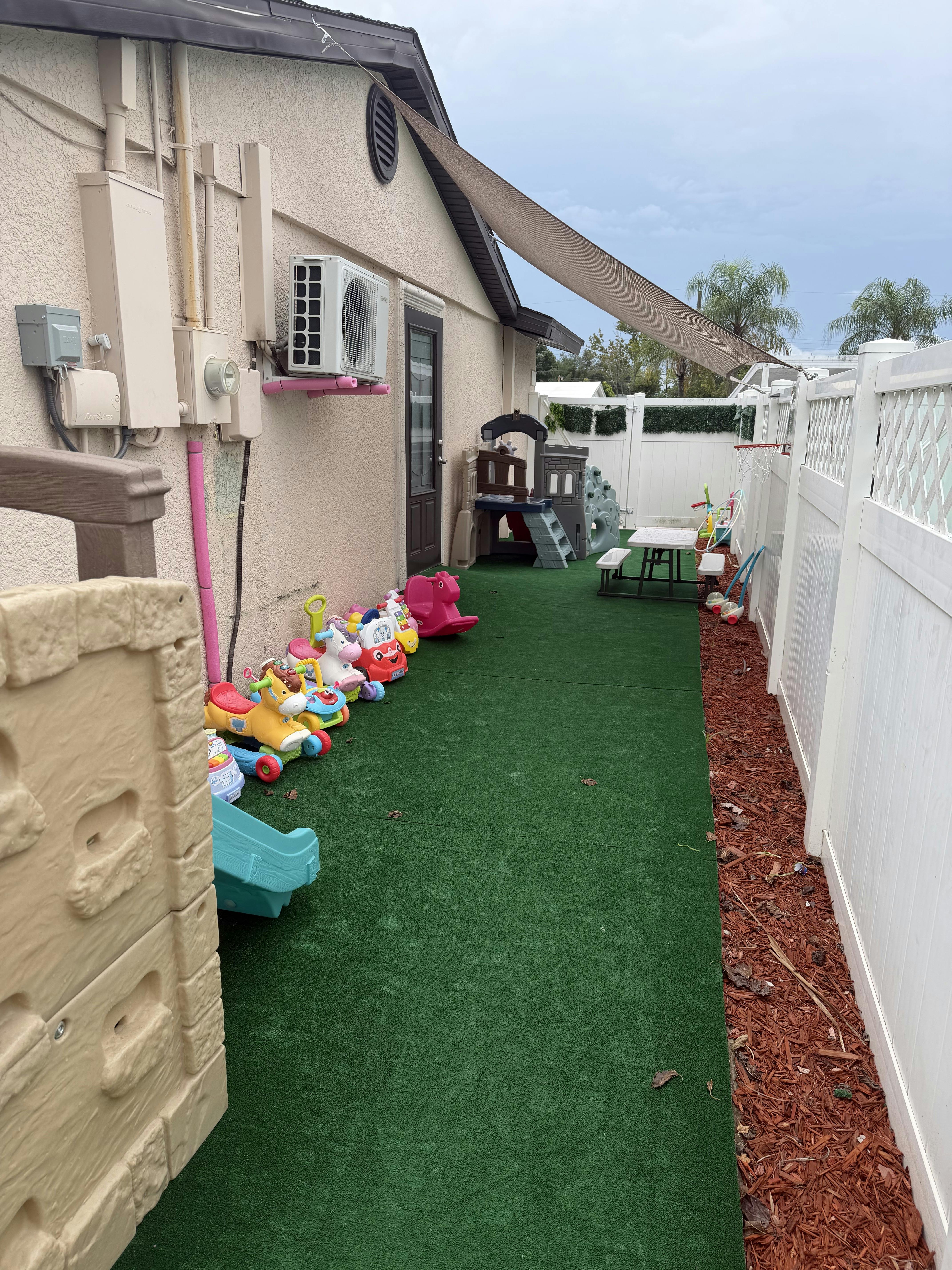 Backyard patio with children's play equipment and toys on synthetic grass