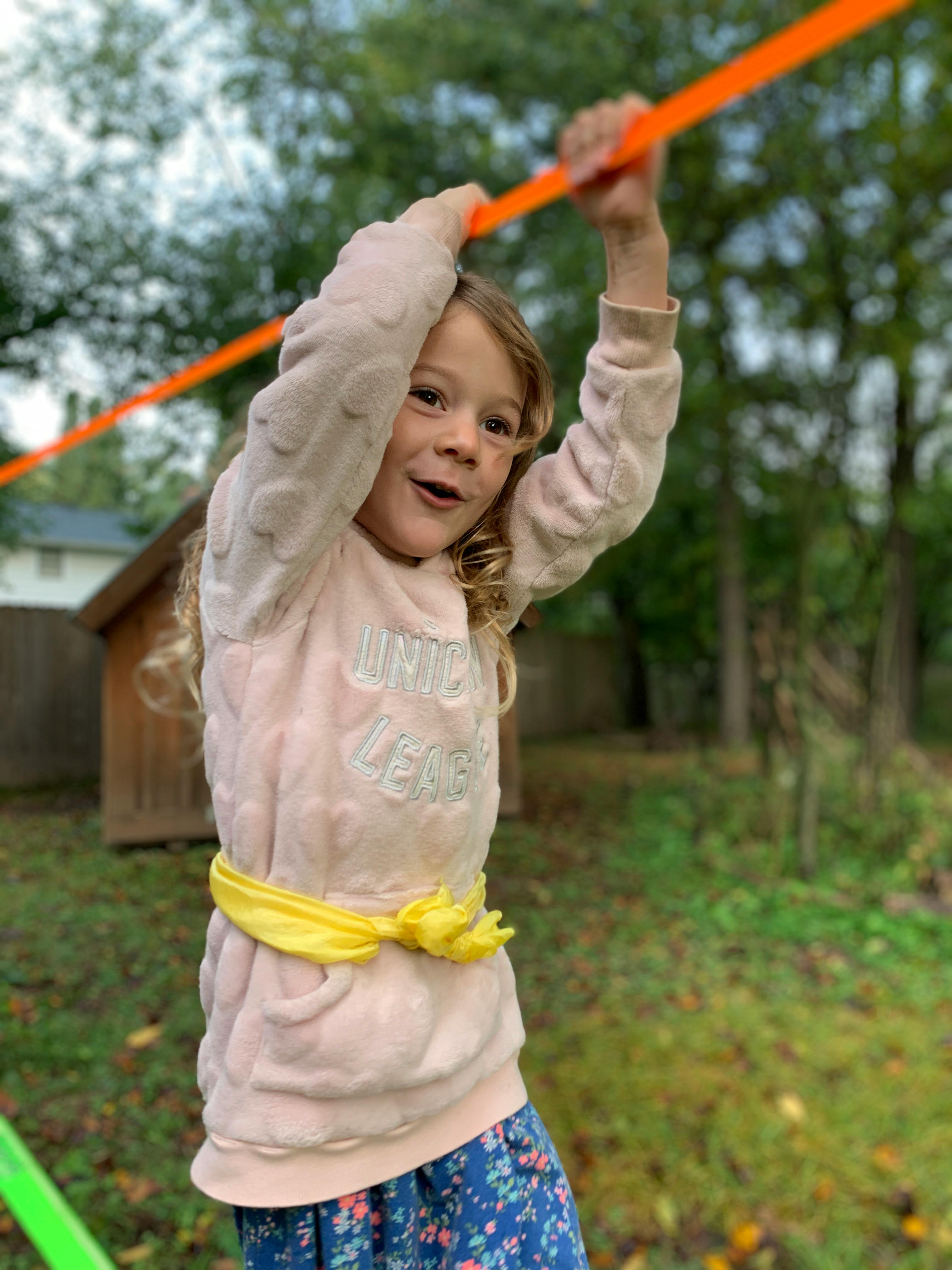 Child holding onto an orange strap outdoors