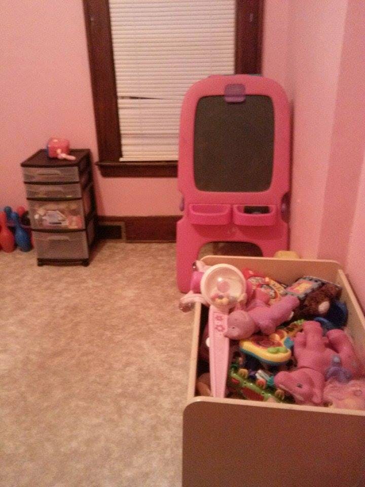 Pink easel and toy box filled with toys in a room