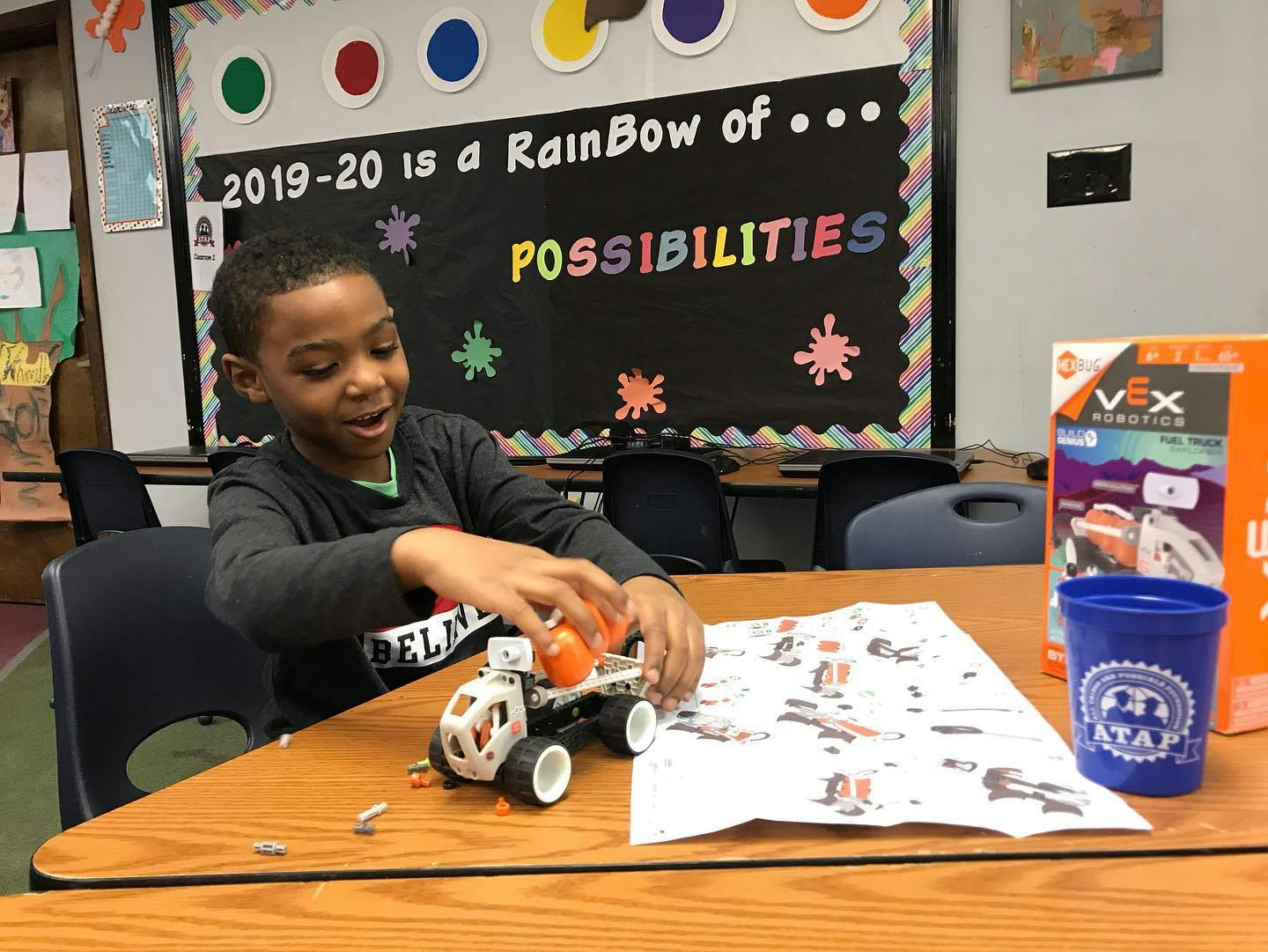 Child building a toy car at a desk in a classroom