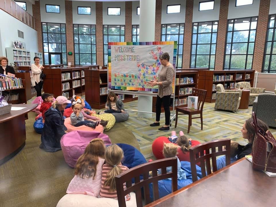 Adult speaking to children and adults sitting on beanbags in a library