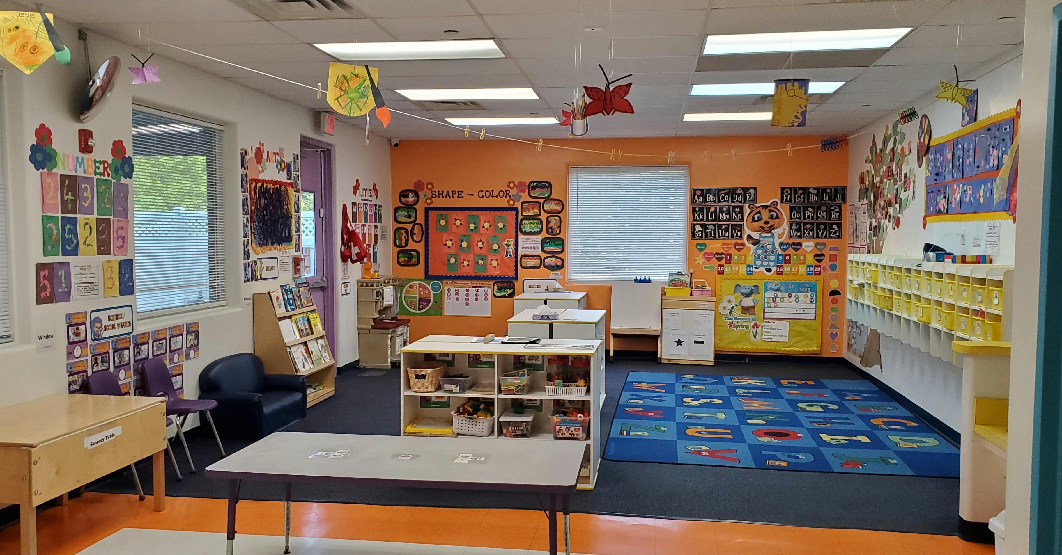 Classroom with colorful decorations, tables, and a blue rug