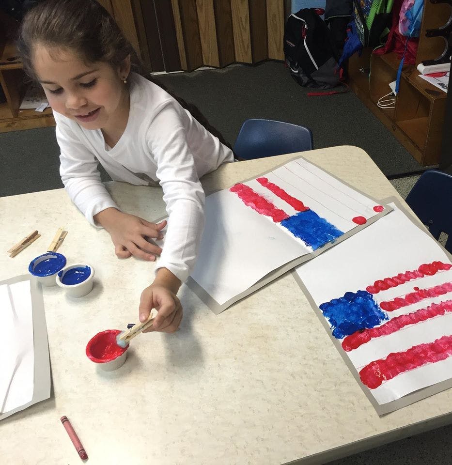 Child painting a flag design with red and blue paint