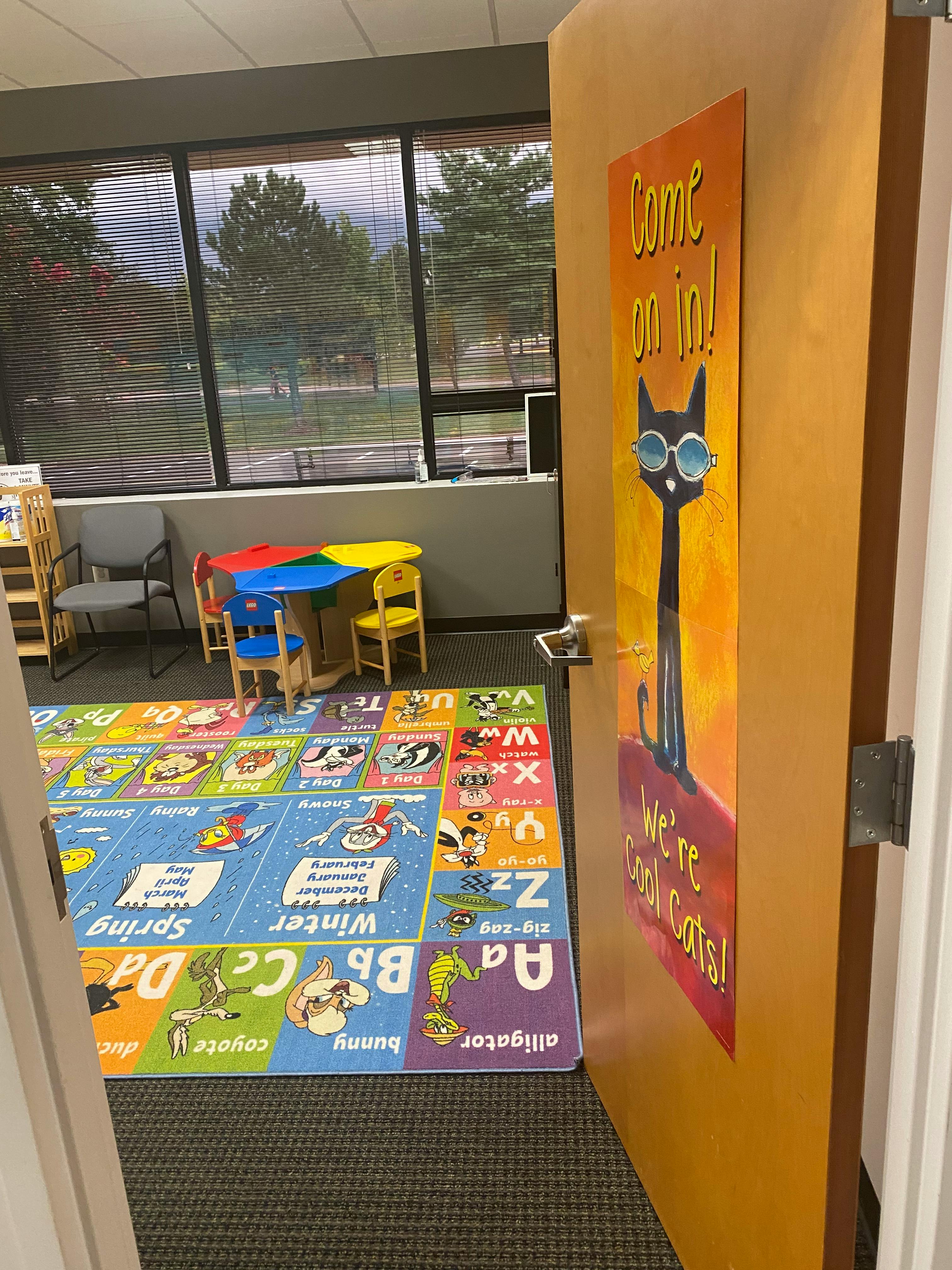 Classroom with a colorful alphabet rug, small table and chairs, and a door sign