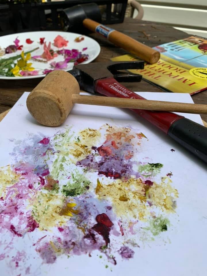 Wooden mallet on paper with smashed flowers and leaves