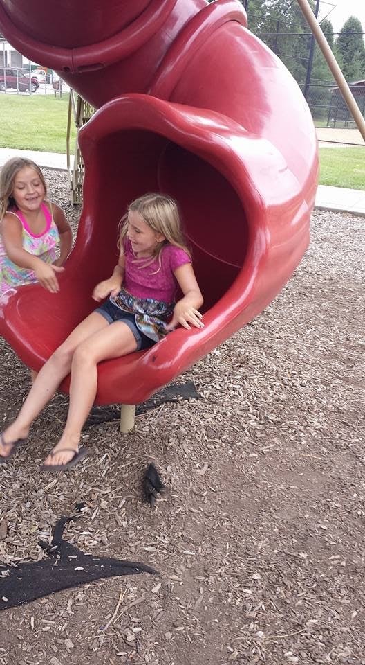 Two children on a red playground slide