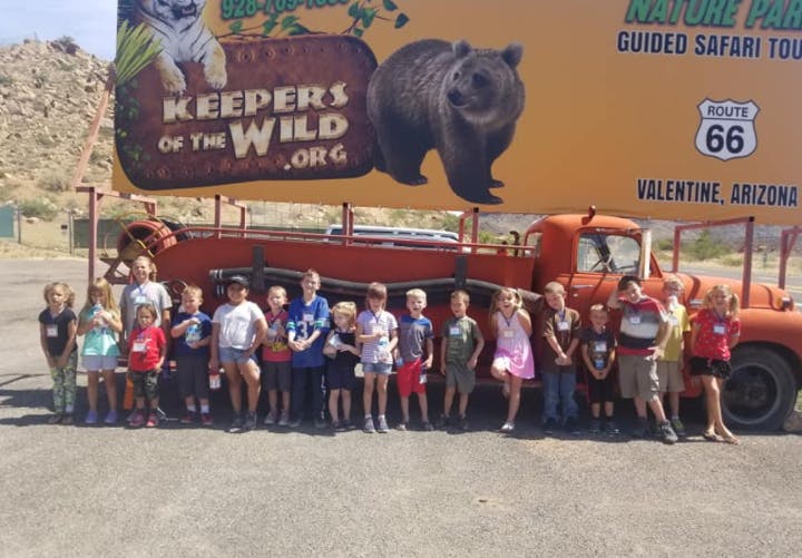 Group of children standing in front of a truck and a large sign
