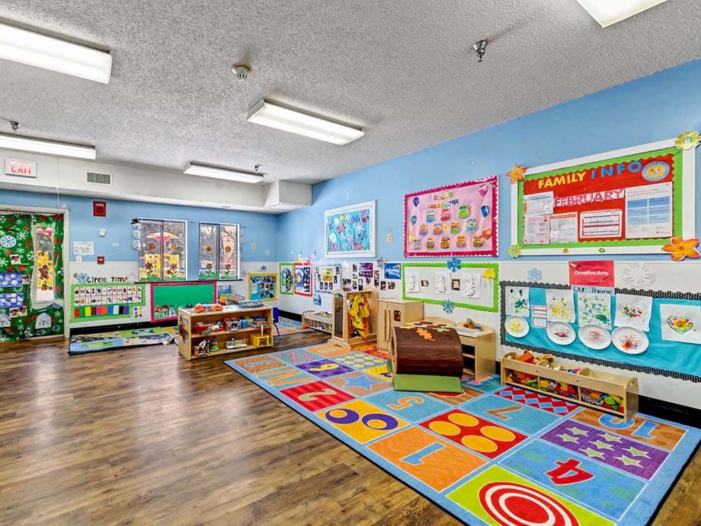 Empty classroom with colorful rug, posters, and educational displays
