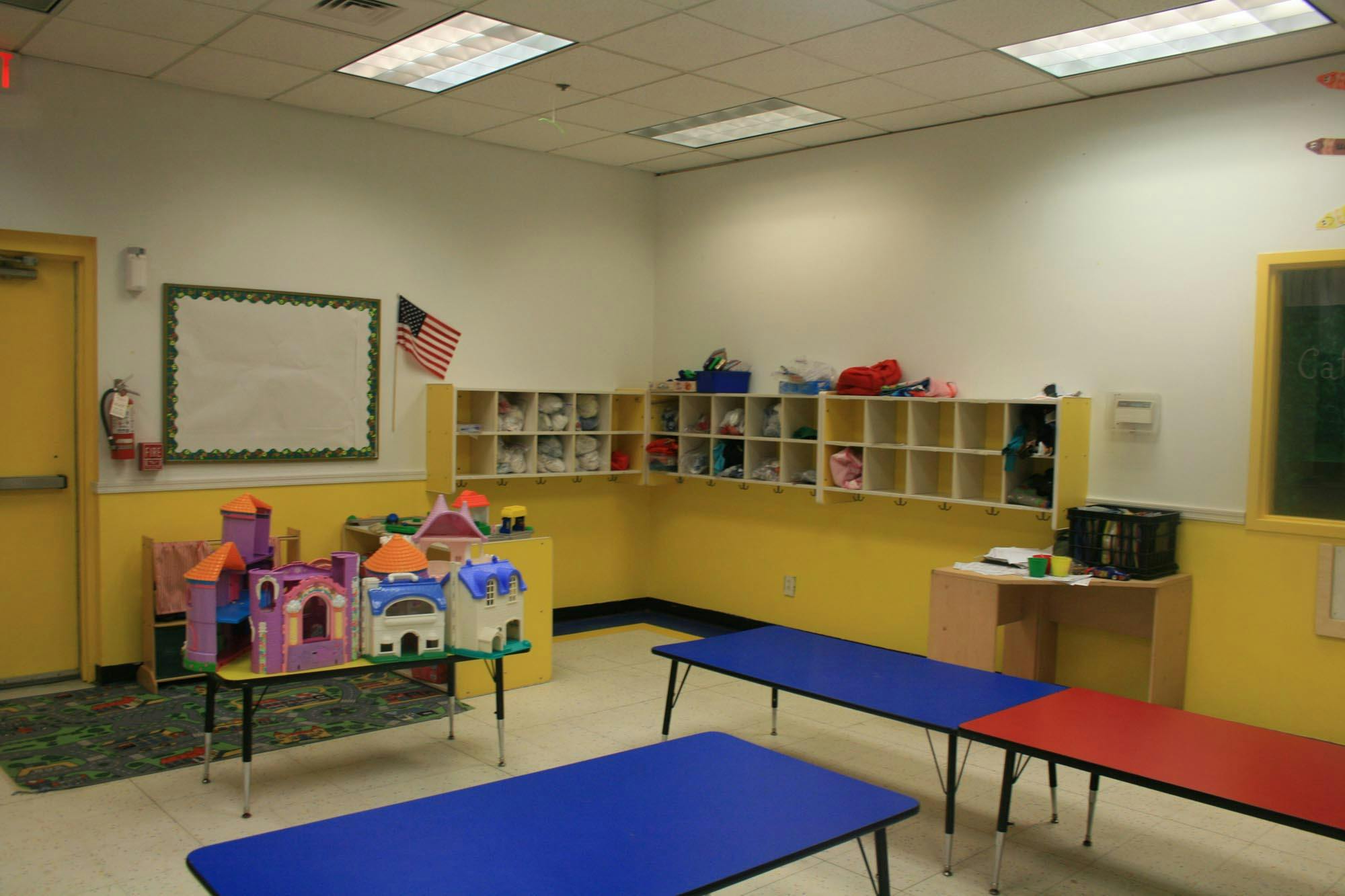 Classroom with blue and red tables, cubbies, and a toy castle