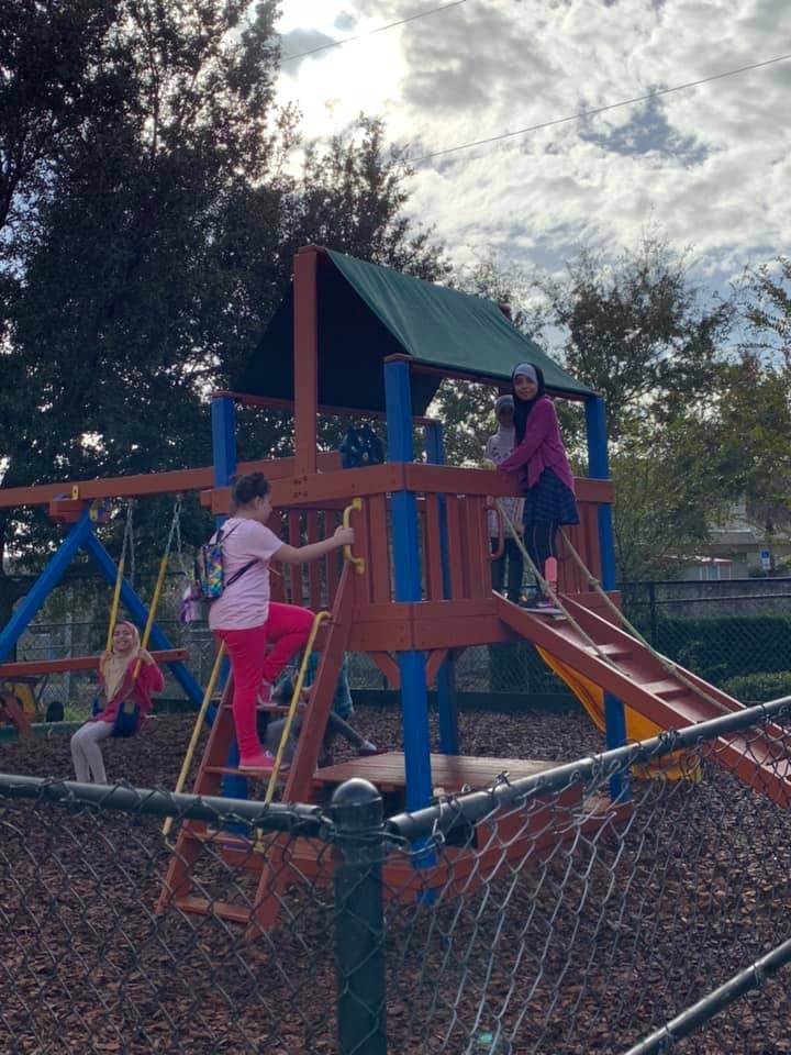 People on a playground structure with slides and swings