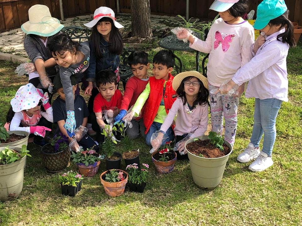 Group of children planting flowers in pots outdoors