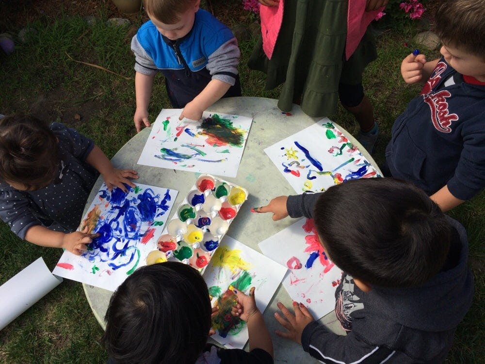 Children painting at a table outdoors