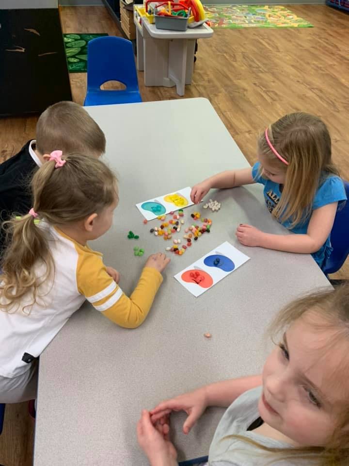 Children playing with colorful small objects and cards at a table
