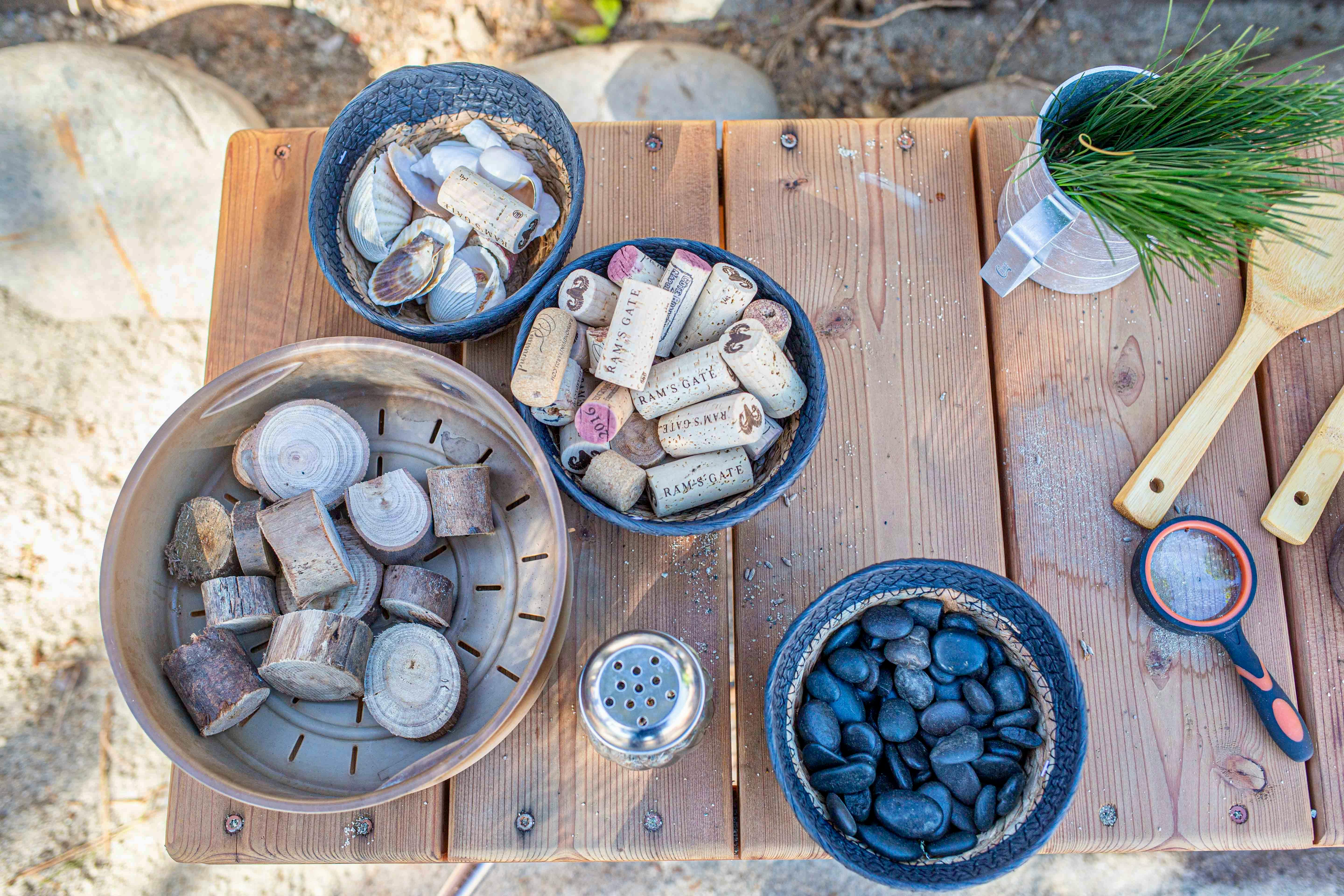 Bowls of corks, shells, and black stones on a wooden table