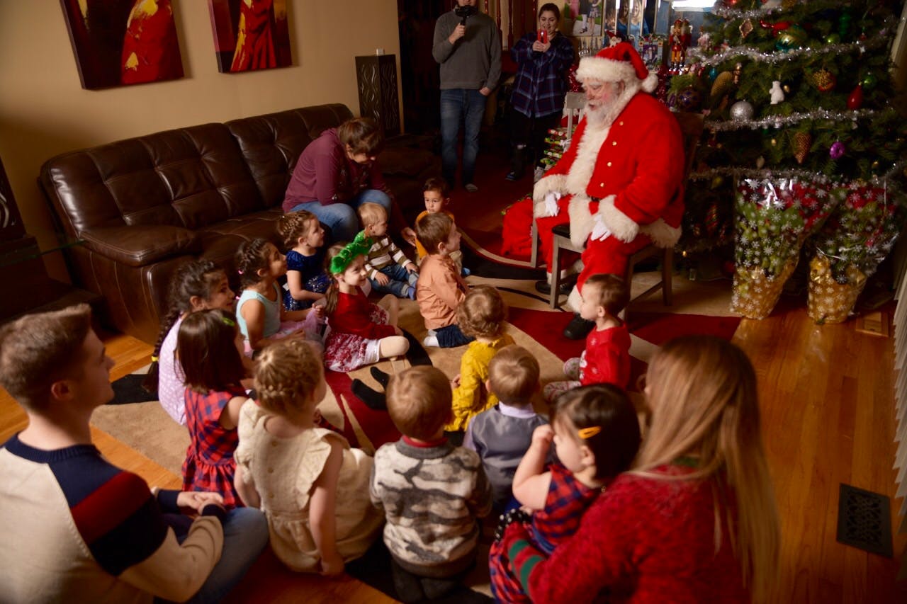 Person dressed as Santa Claus sitting with children