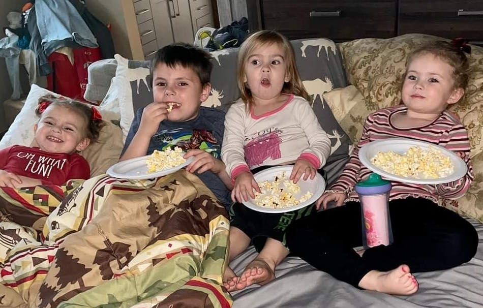 Four children eating popcorn on a couch