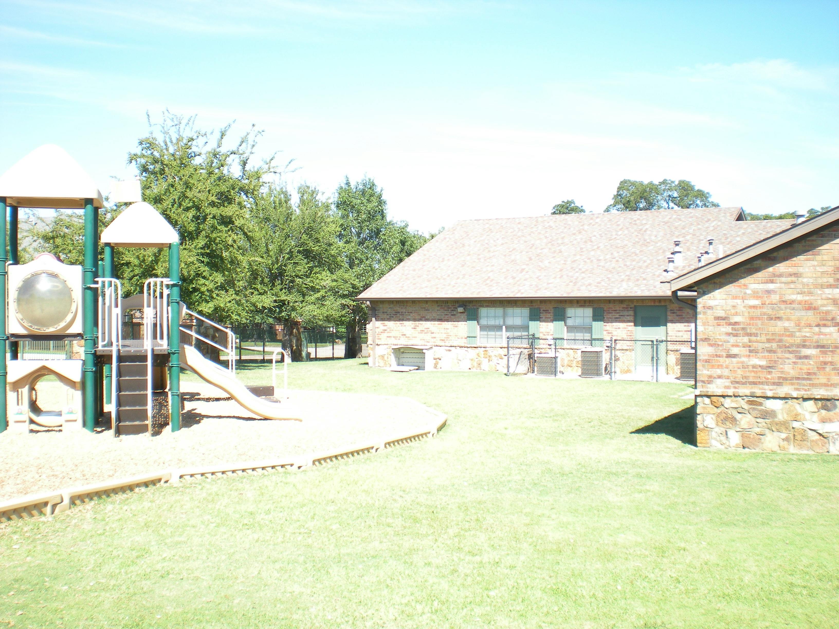 Playground structure with slides next to a brick building
