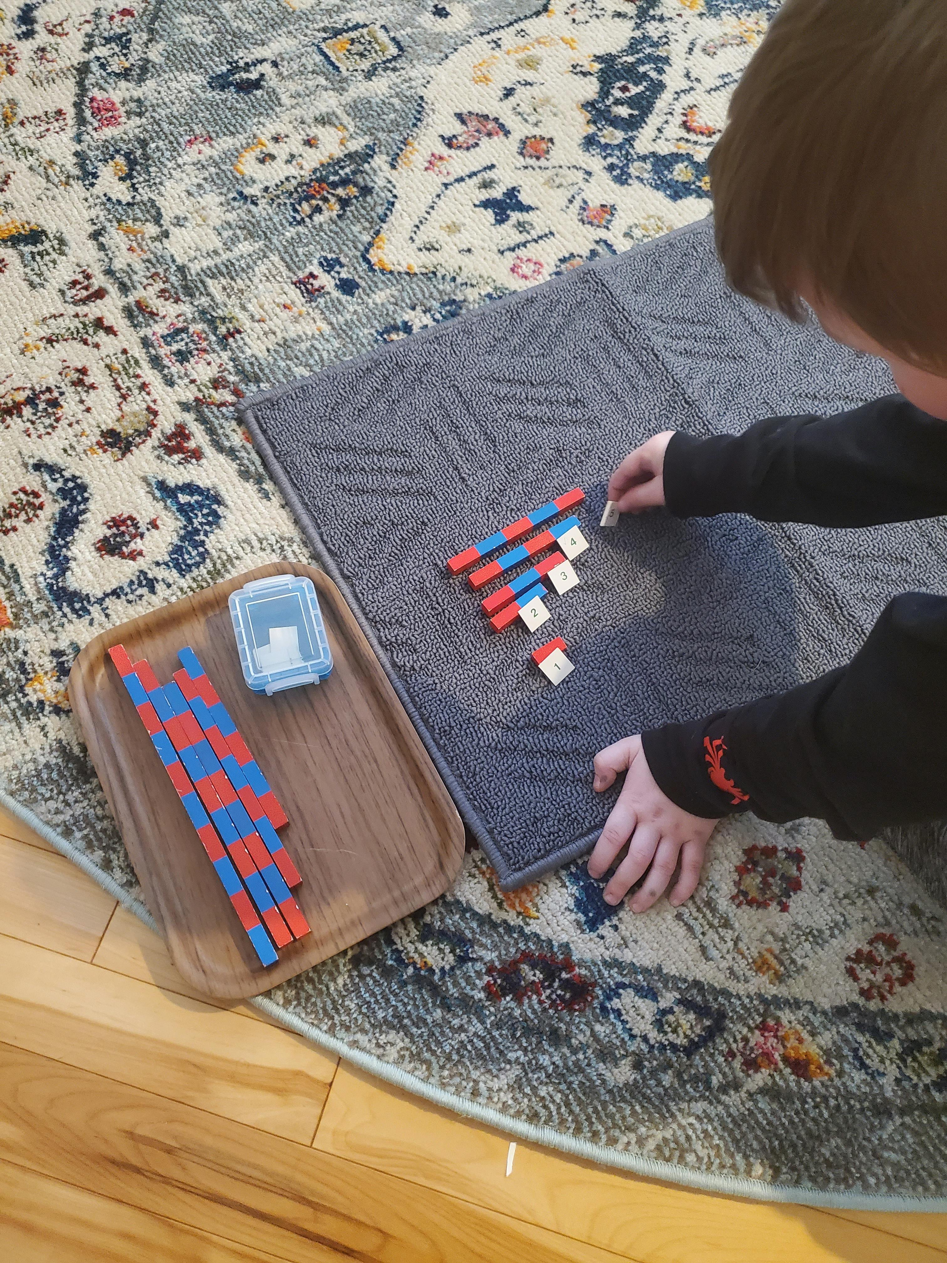 Child playing with red and blue math counting blocks on a gray mat