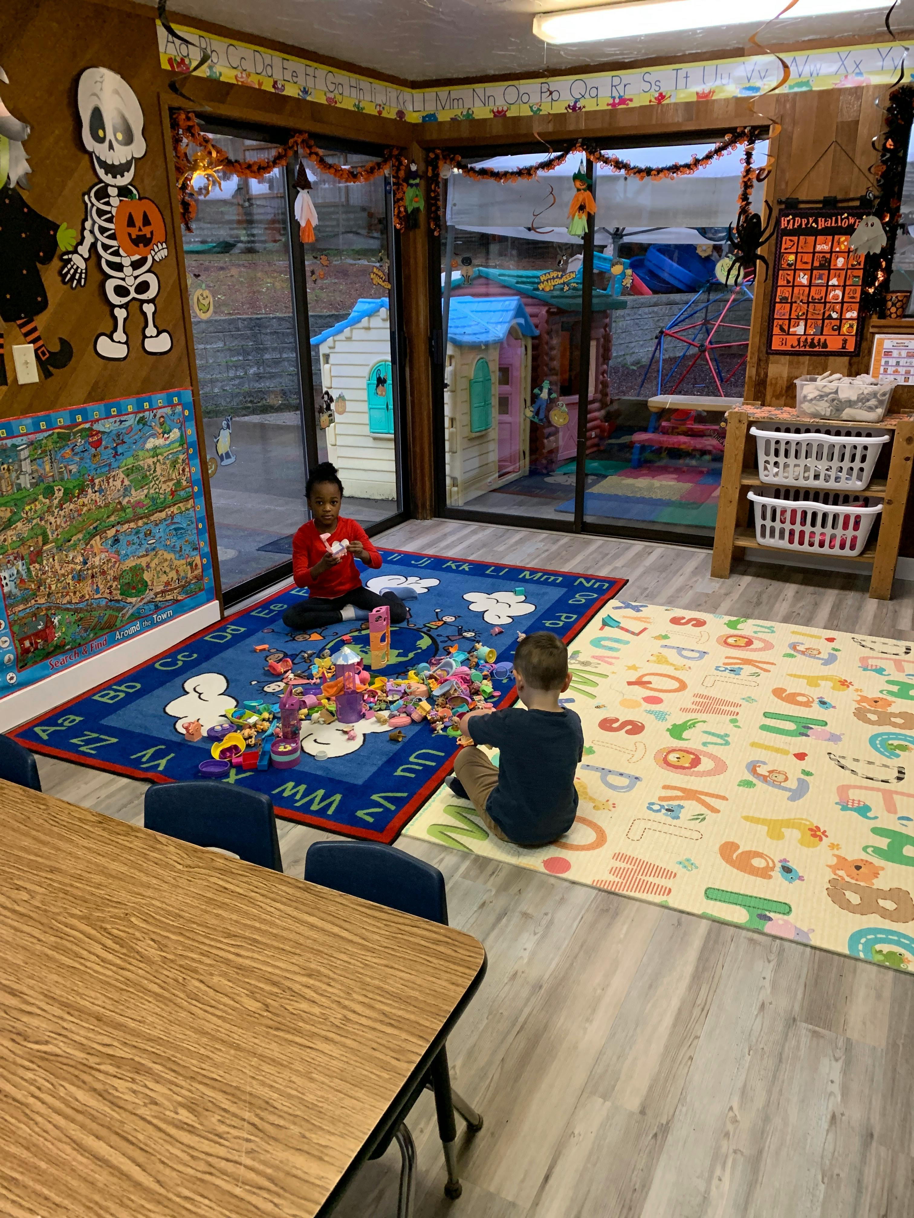 Two children playing with toys on rugs in a room