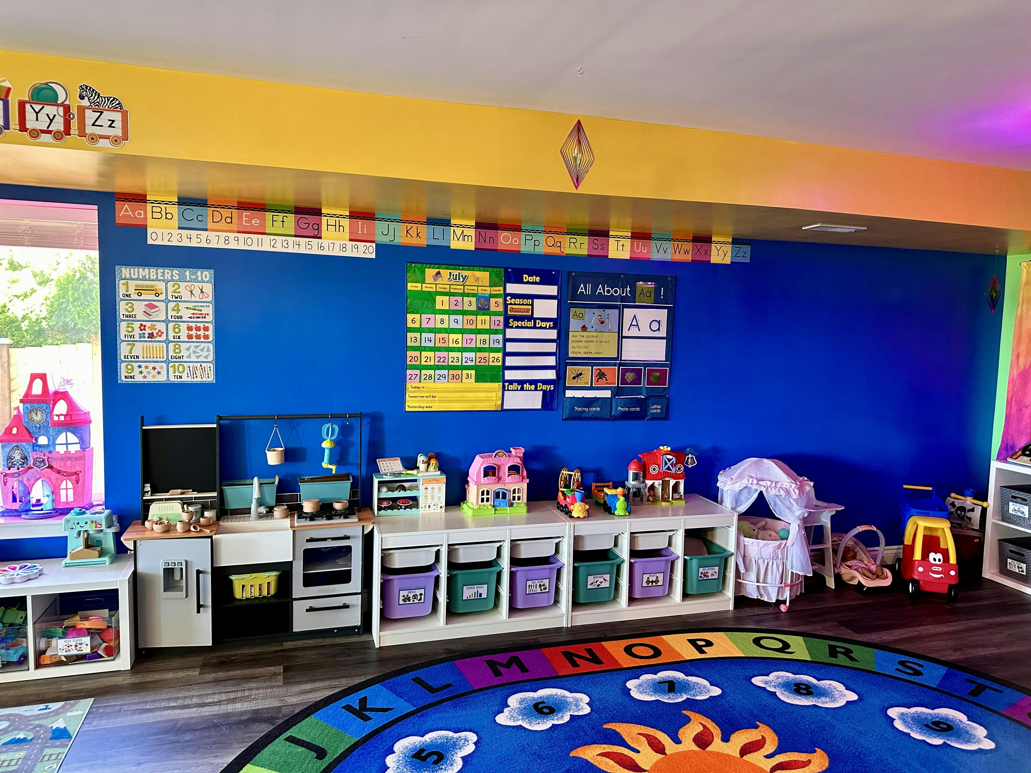 Playroom with toy kitchen, storage bins, and a colorful alphabet rug