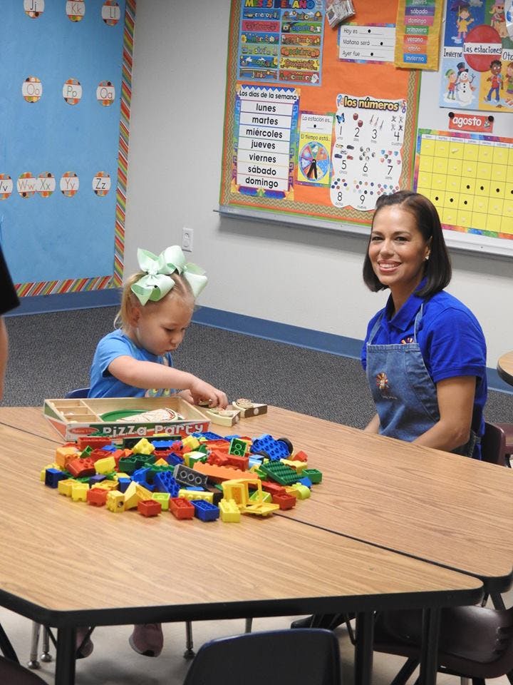 Child playing with blocks at a table with an adult