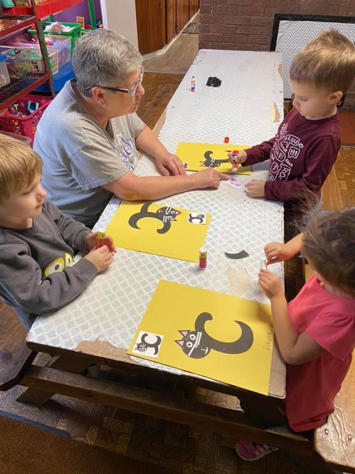 Adult and three children doing crafts at a table