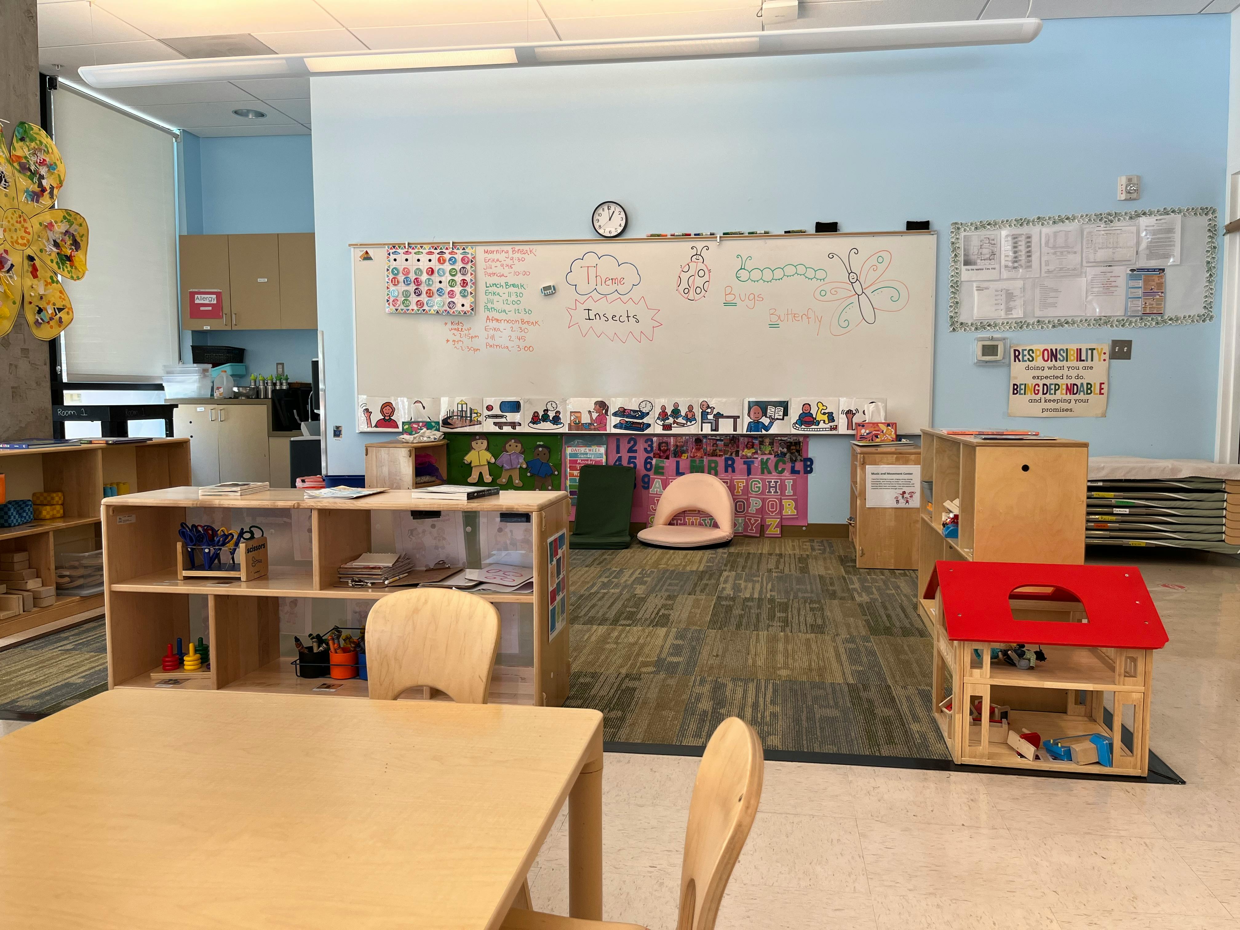 Classroom with tables, shelves, whiteboard, and play area