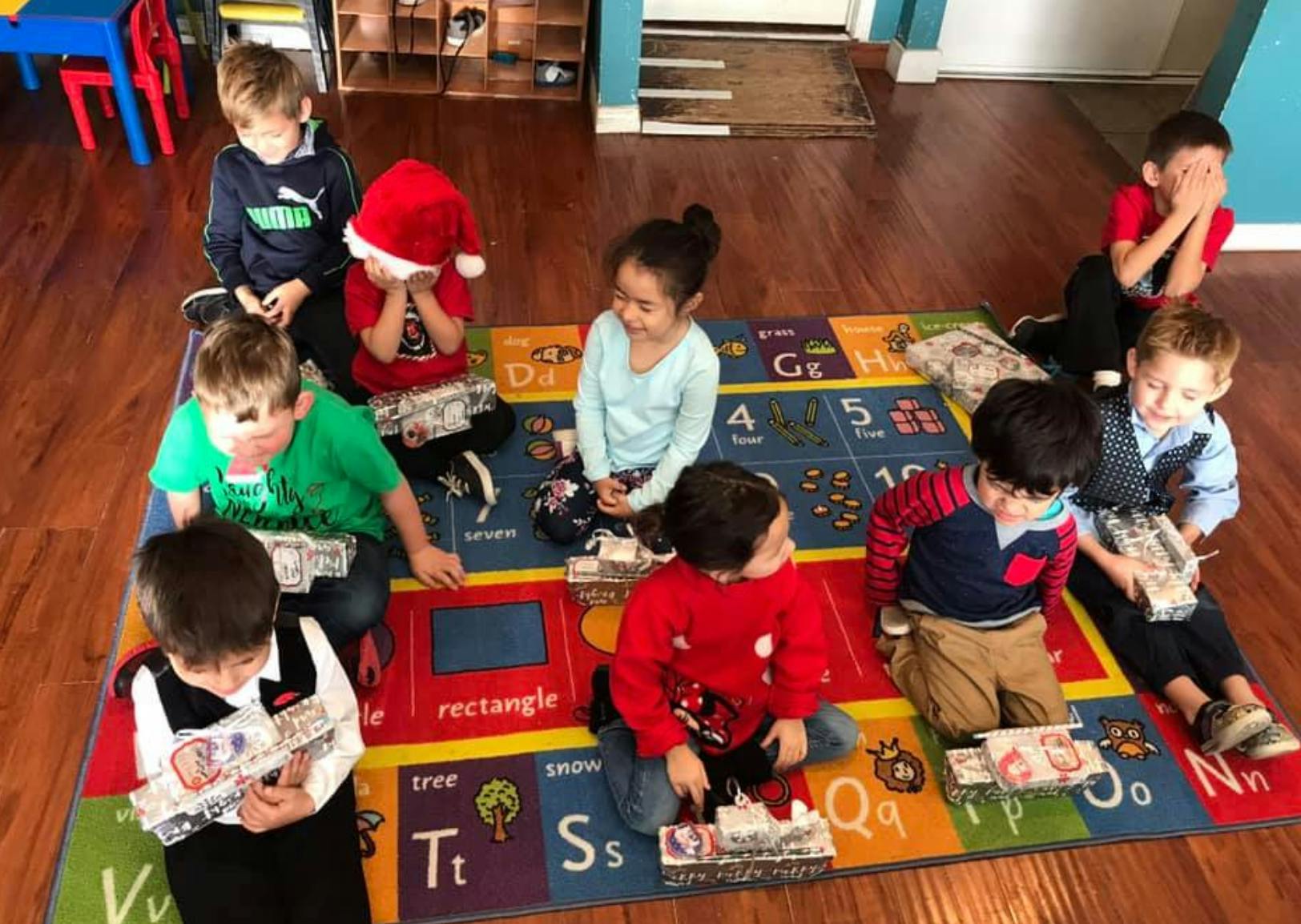 Children sitting on a colorful rug looking at items in-hand items