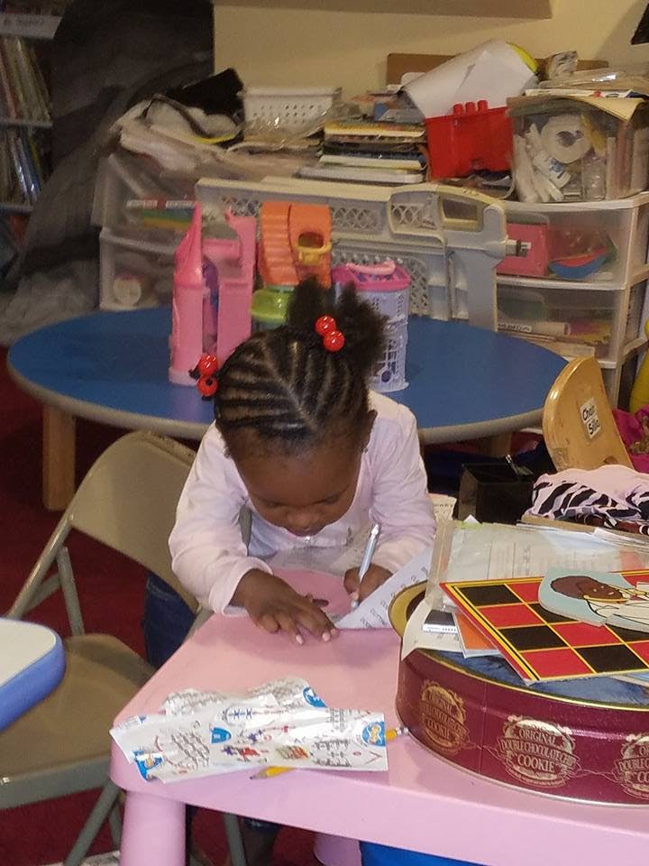 Child writing on paper at a small table