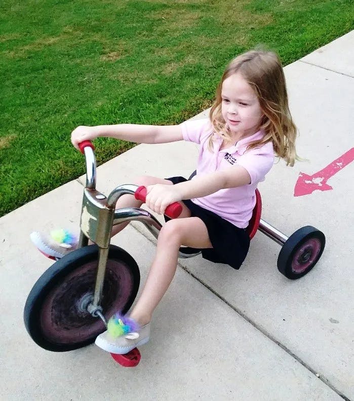 Child riding a tricycle on a sidewalk