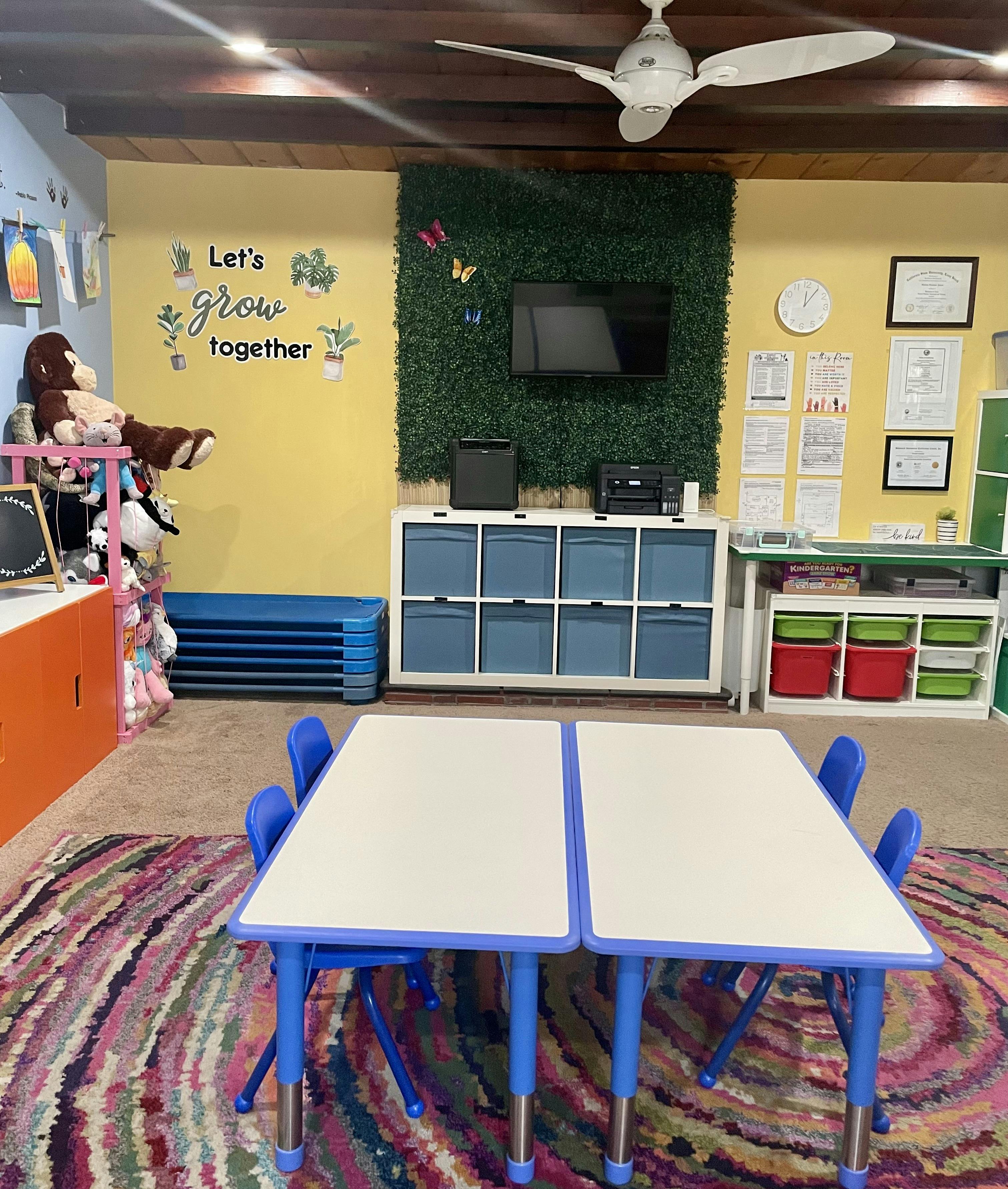 Classroom with small tables and chairs, storage units, and a wall decoration
