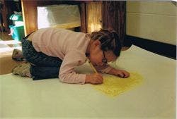 Child kneeling and drawing on paper