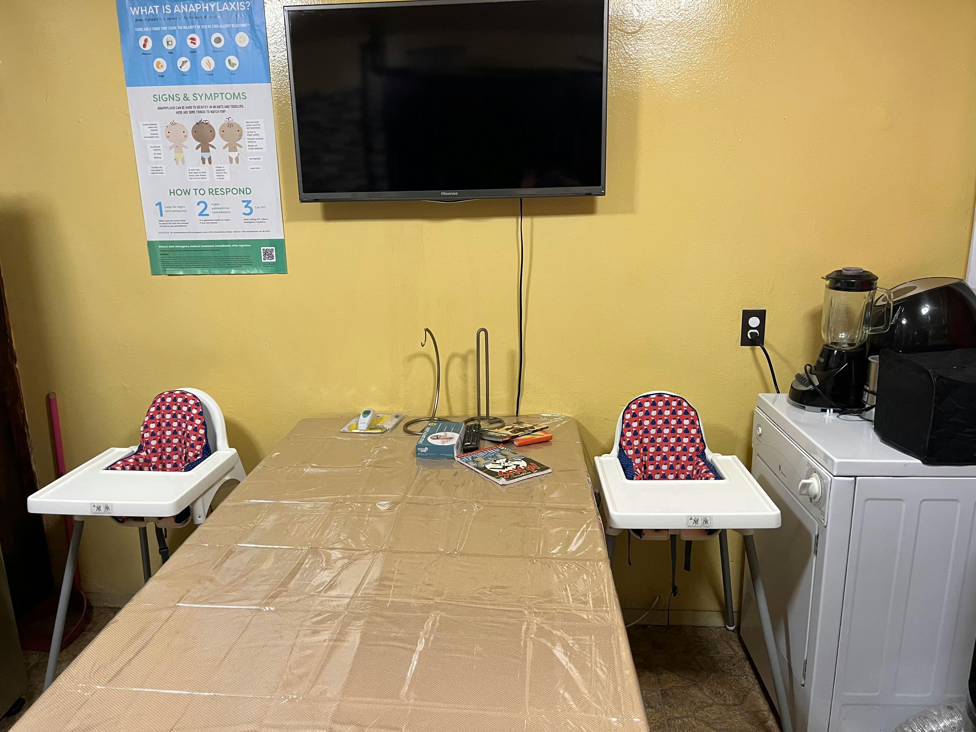 Two high chairs at a table with a television mounted on the wall