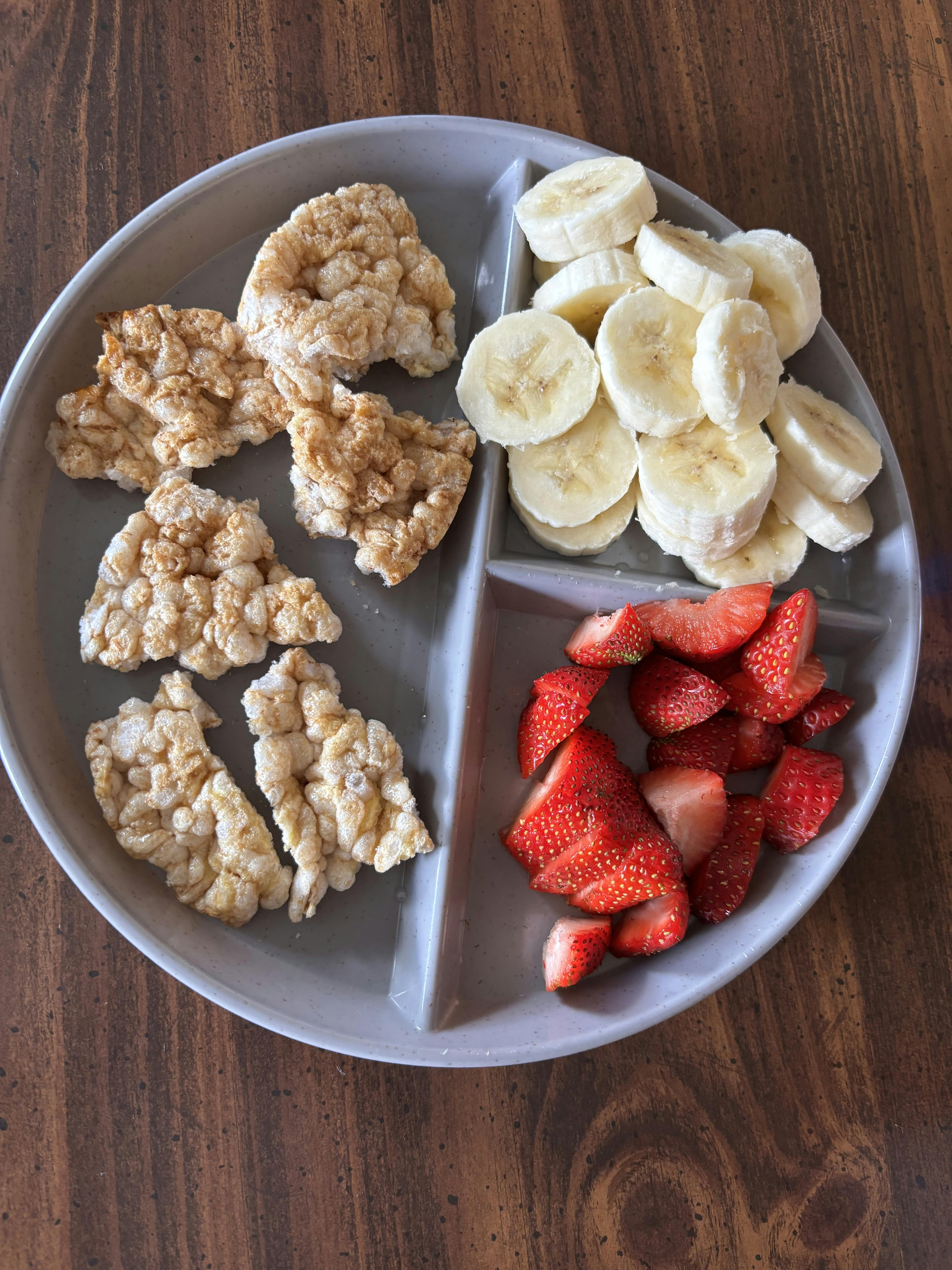 Sectioned plate with rice cakes, sliced bananas, and cut strawberries
