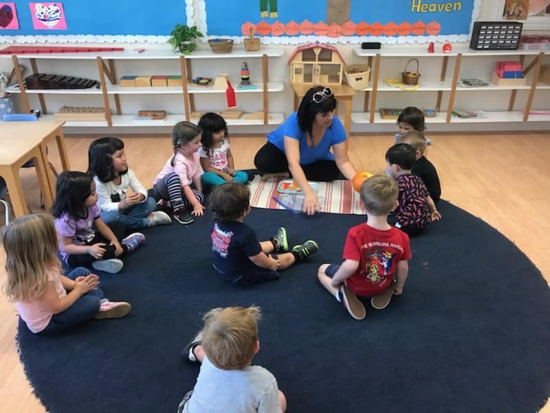 Adult and children sitting on a rug in a classroom