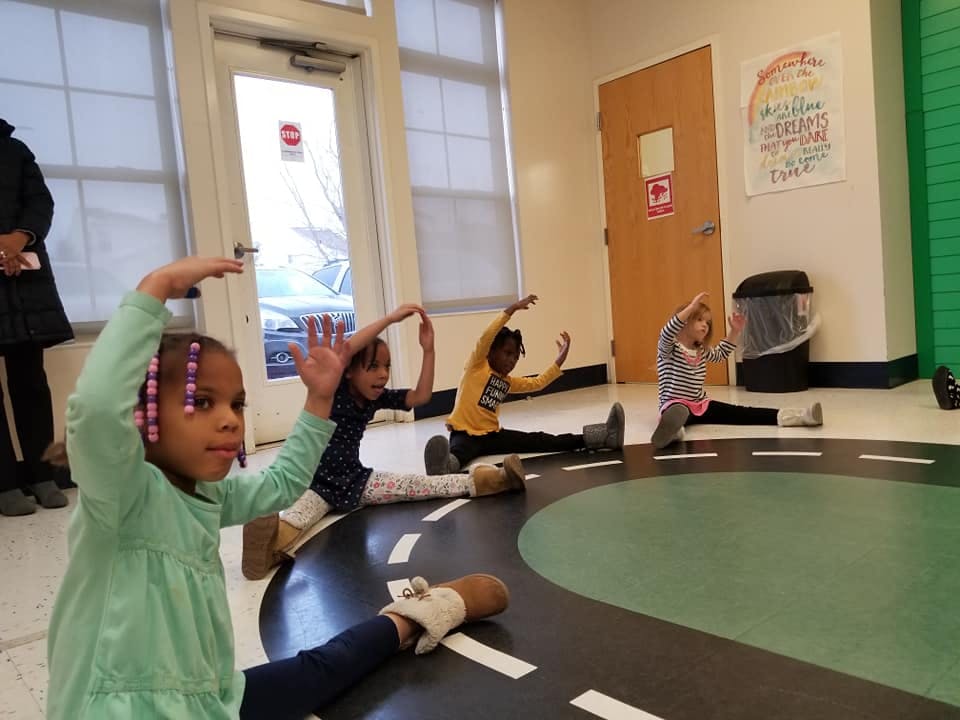 Children sitting on the floor with arms raised