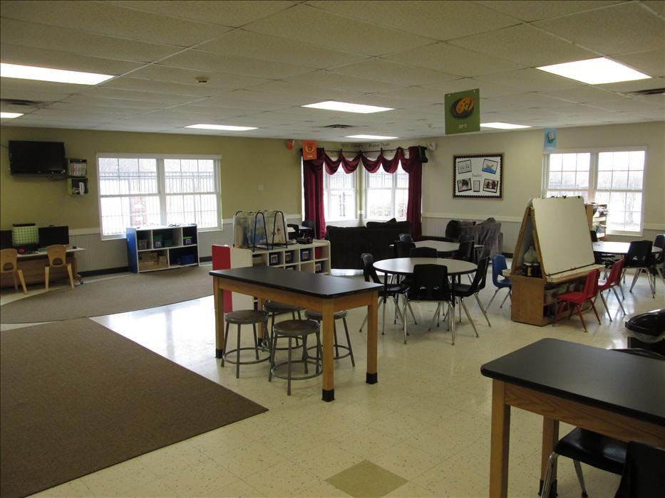 An empty classroom with desks, chairs, tables, and computers